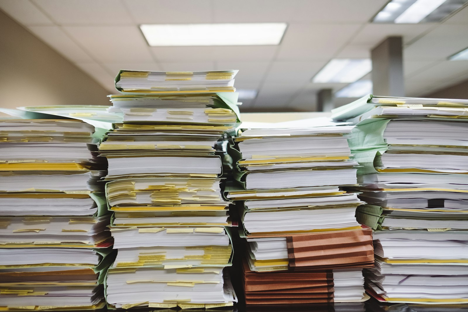 Tall stacks of paper folders and documents on an office desk — a picture of disorganised complaint handling